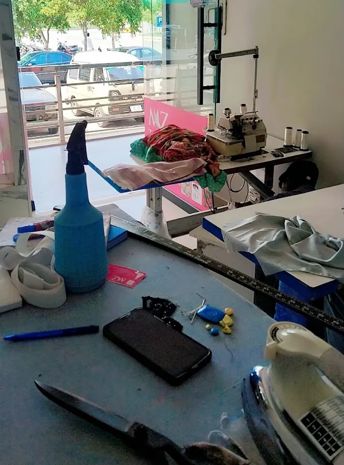 The cutting table with scissors, iron and an overlock machine